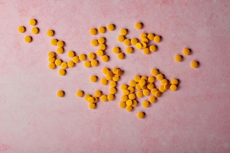 yellow beelith pills lying against a pink background